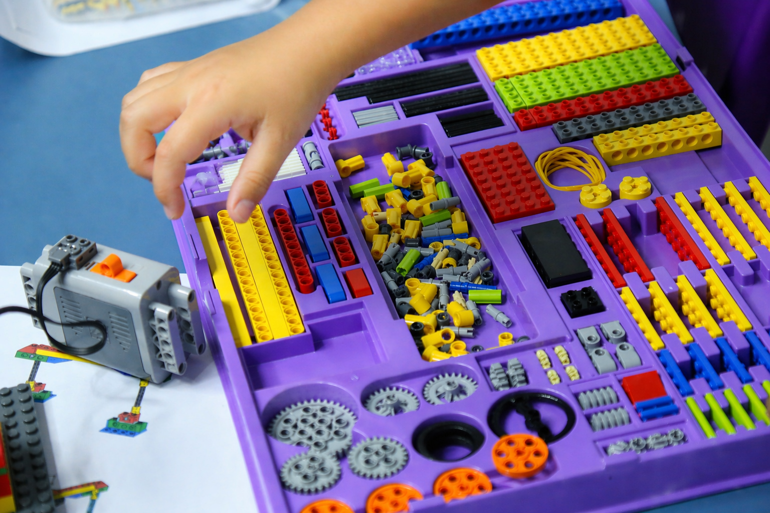 Mão escolhendo peças coloridas de um kit de robótica